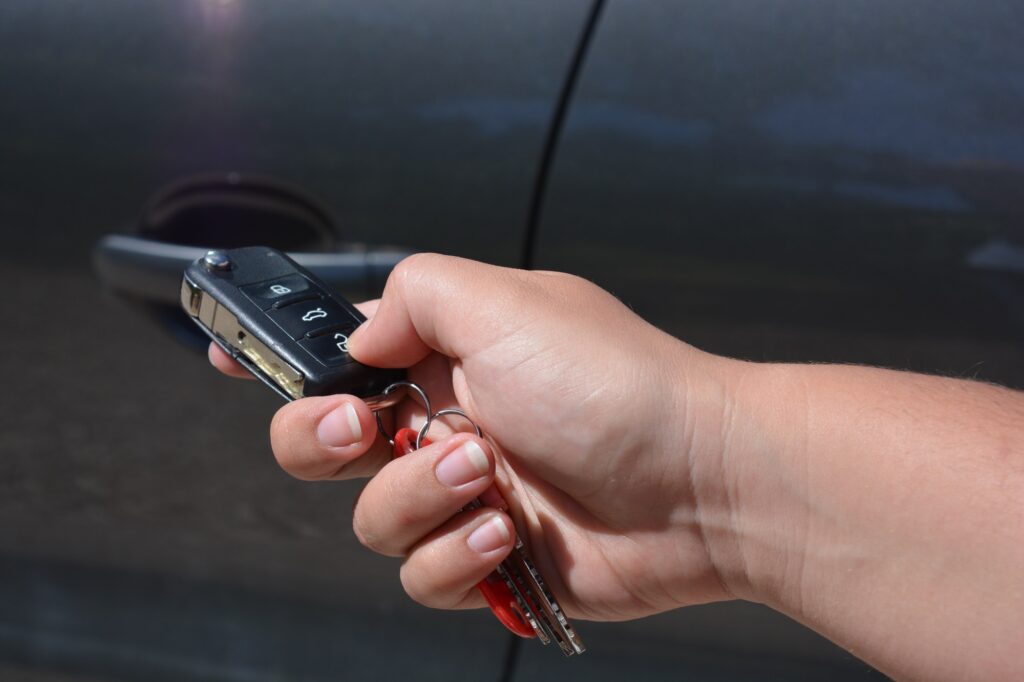 Woman locking or unlocking car door with remote key